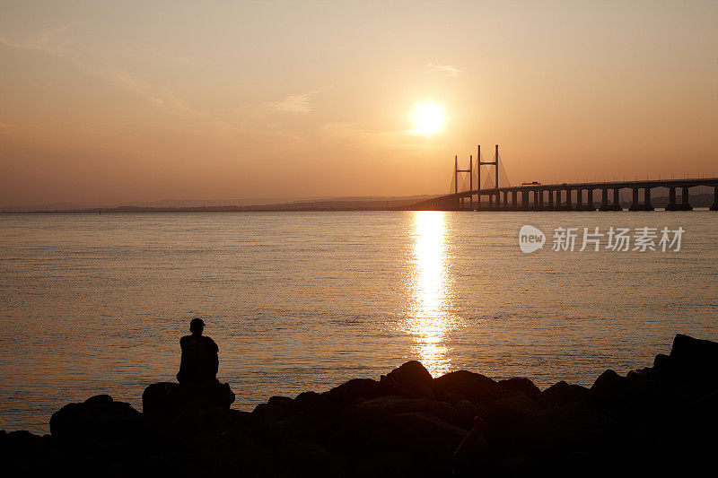 日落时在海边沉思的人