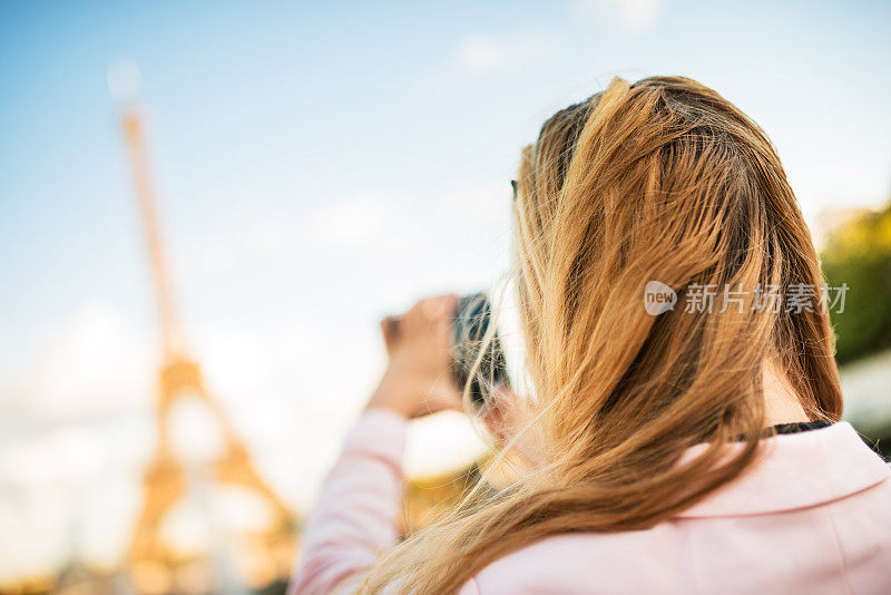 一名女子在巴黎埃菲尔铁塔上拍照