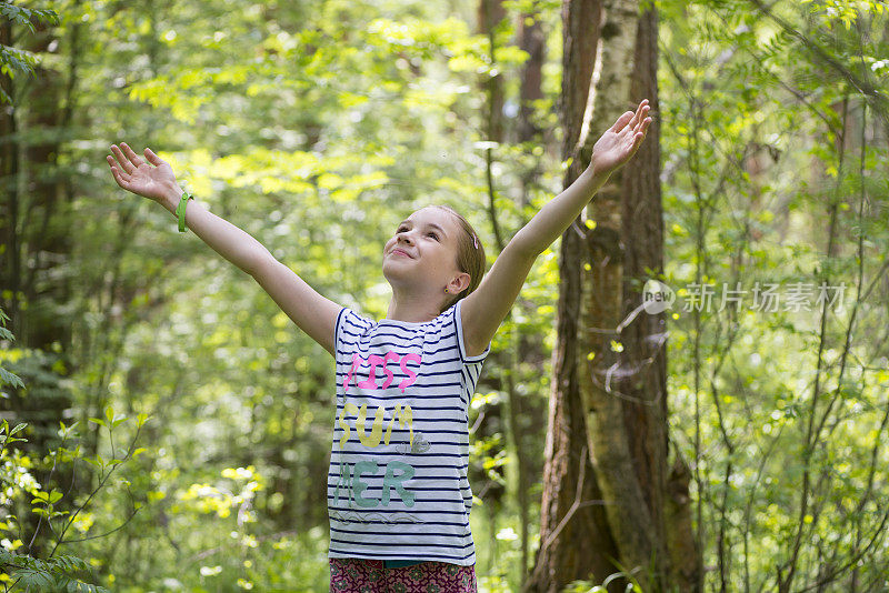 快乐的少女在森林里举起双手享受自由