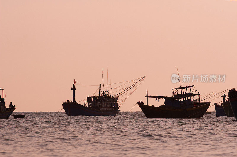 日落时海面上渔船的剪影