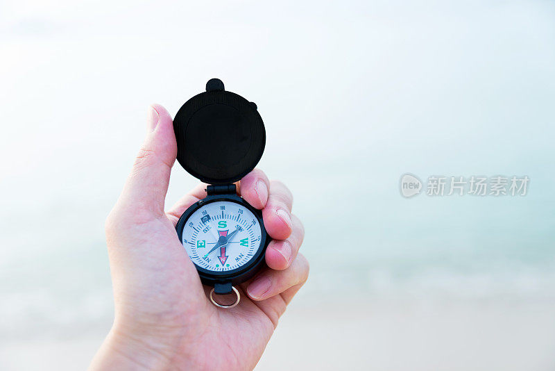 在海滩上，一个手持指南针的男人