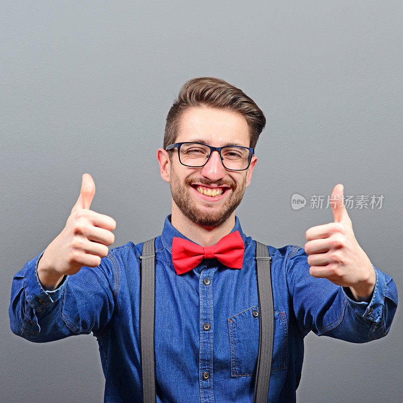 一个男人在灰色背景下竖起大拇指或ok手势的肖像
