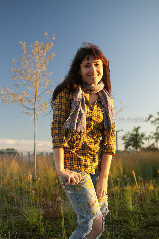 快乐的学生女孩与黄色衬衫牛仔裤围巾在野外