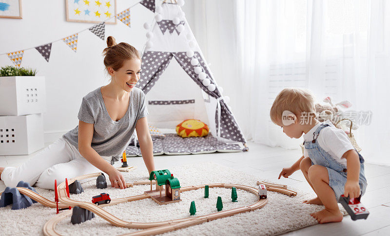快乐的家庭妈妈和孩子儿子在玩具铁路玩在游戏室