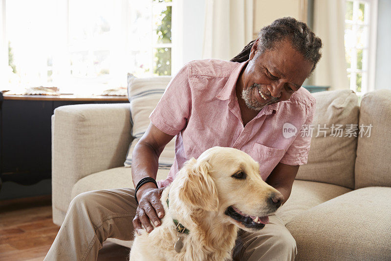 一位老人和宠物拉布拉多狗坐在家里的沙发上