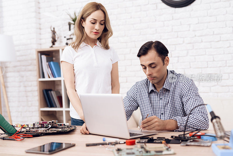 这个人是无线电技术员。一个男人正在为一个女人修理笔记本电脑。