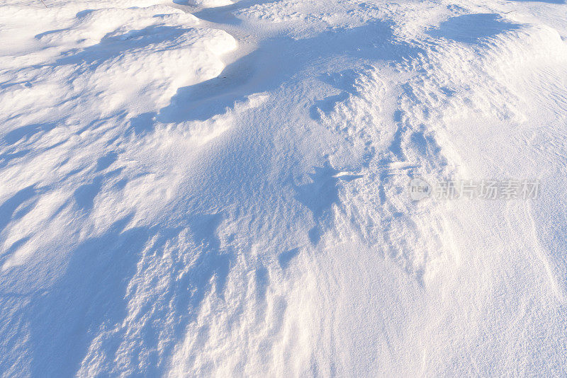 雪堆、风在雪面上雕刻出图案。