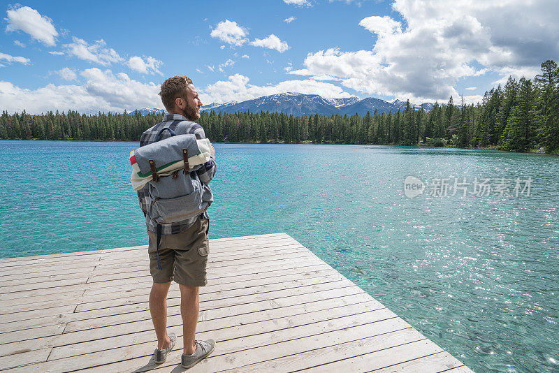 一个年轻人站在湖边的码头上看风景
