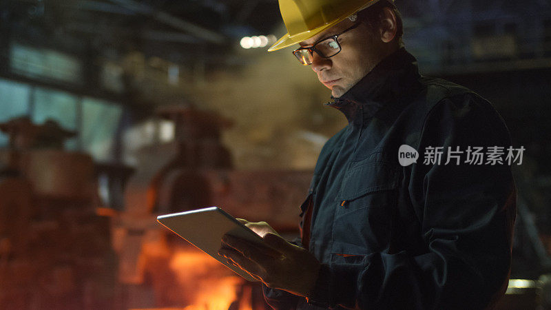 眼镜工程师在铸造厂使用平板电脑。工业环境。