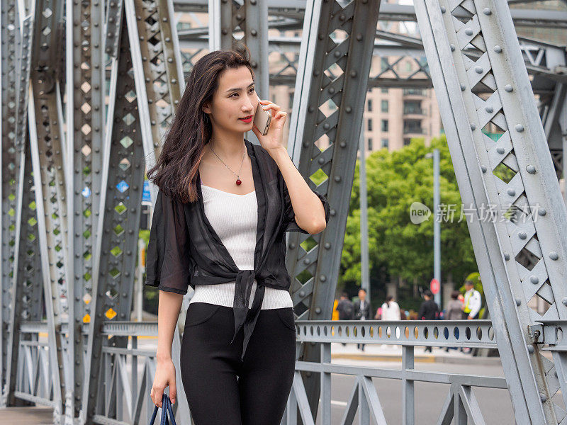 快乐的成年亚洲女人的电话，与上海花园桥的背景。