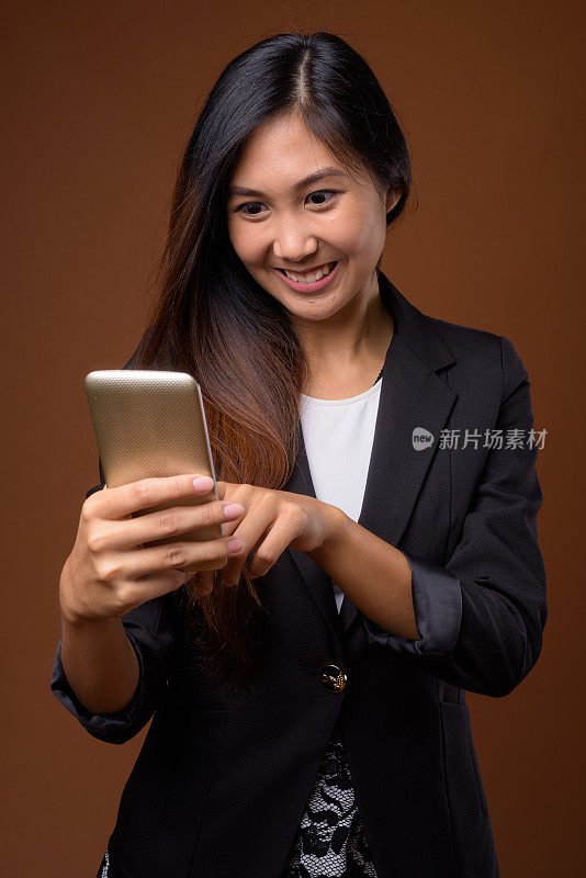 工作室拍摄的年轻美丽的亚洲女商人使用手机在彩色背景