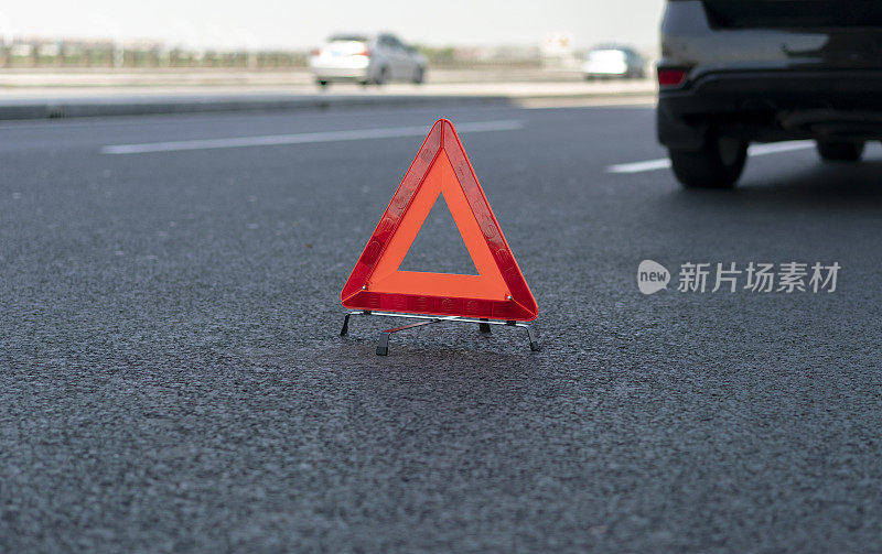 路上一辆车后面有三角形警告标志