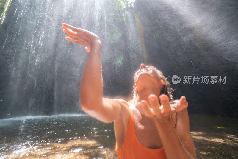 热带雨林里的年轻女子仰望着美丽的阳光用手触摸着雨滴。人们旅游是享受自然和生活的理念