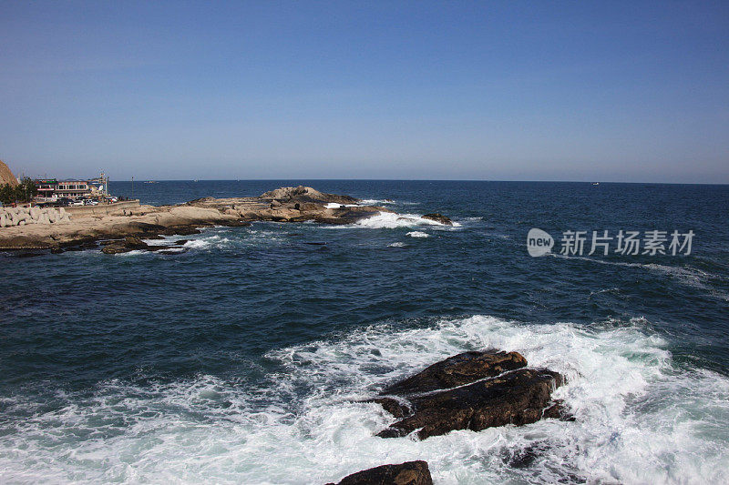 碧空映衬海中岩景