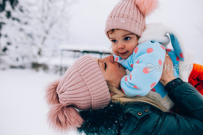 快乐的妈妈喜欢和她的孩子在雪地里玩