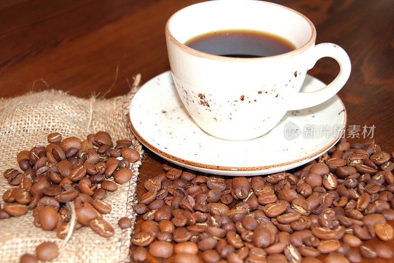 木质背景上的咖啡杯和咖啡豆。前视图。