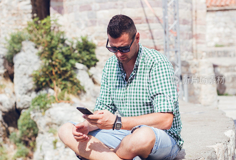 在黑山老城巴德瓦，一名男子在户外使用手机。