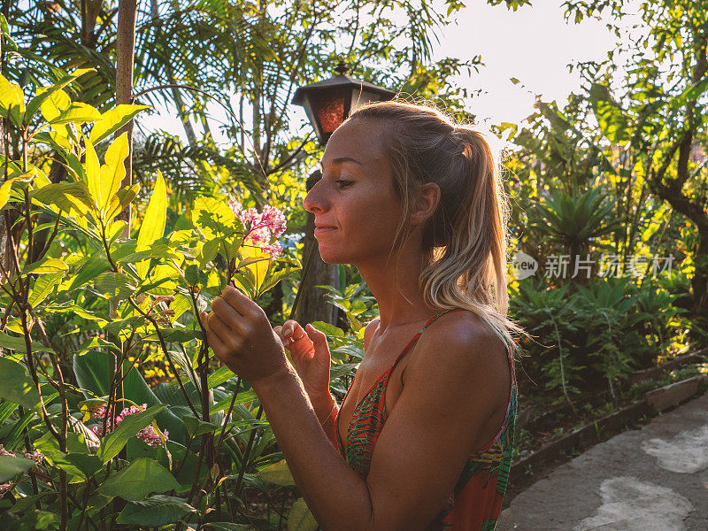 年轻女子照顾植物在异国情调的花园