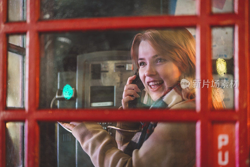 在伦敦的电话亭里微笑着说话的女孩