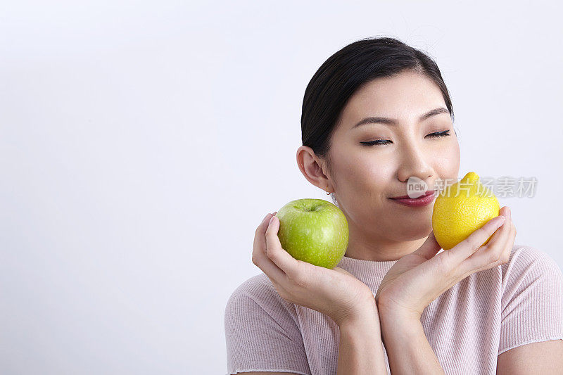 特写的中国民族妇女比较苹果和柠檬