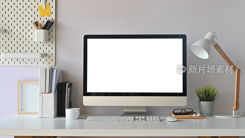 创造性的工作空间。办公室办公桌上的白色黑屏电脑。设备表。
