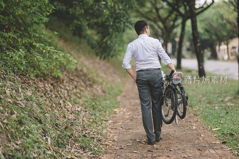 一名亚洲华人白领管理人员与折叠自行车的通勤后视图