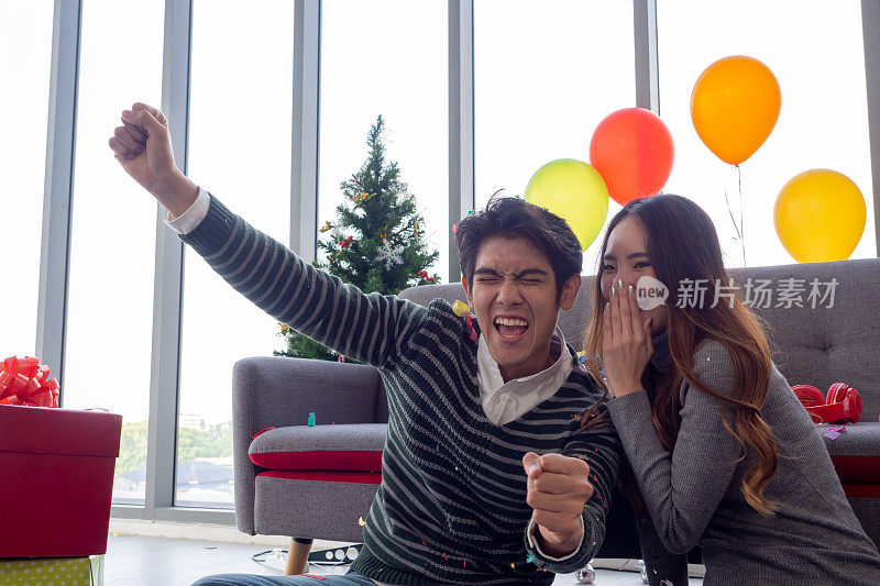 亚洲夫妇窃窃私语，并举手表示新年成功、喜讯或怀孕。