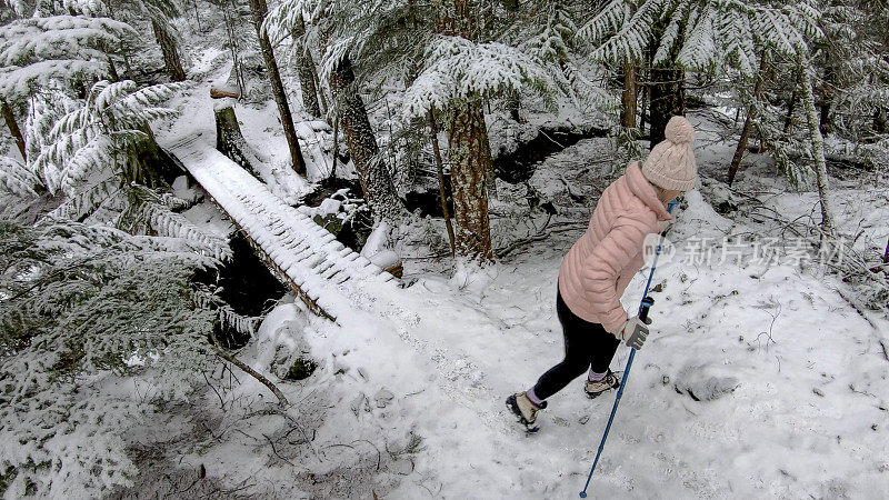 女性徒步旅行者在一条被雪覆盖的小径上行走