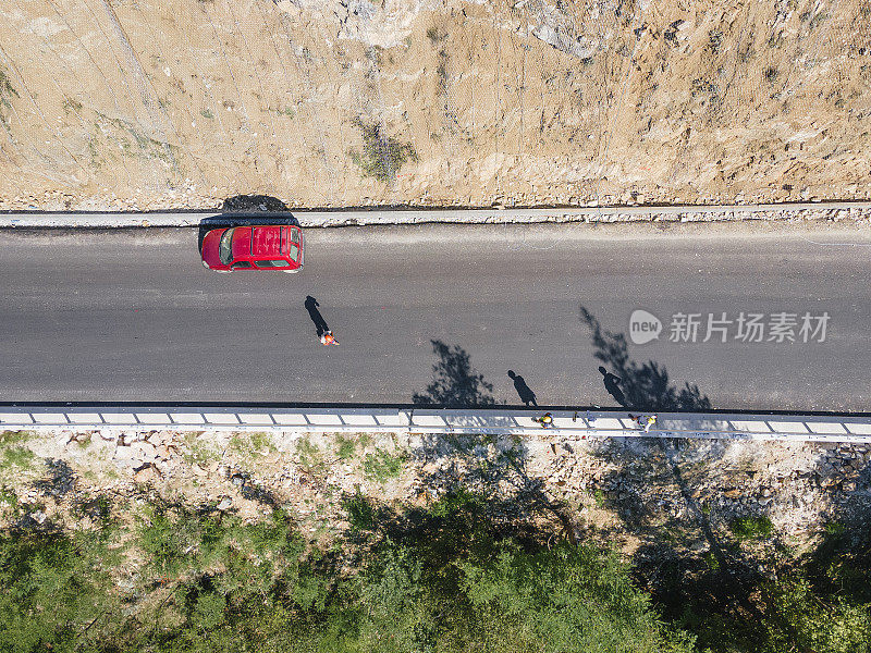 一辆红色汽车停在山间高速公路的侧面。鸟瞰图直接俯瞰在山上的一条高速公路，俯视图。假期。