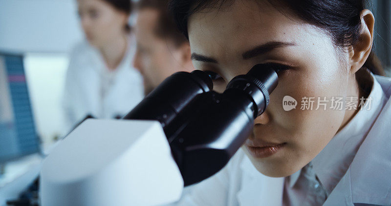 未来实验室内部。亚洲女医生使用显微镜