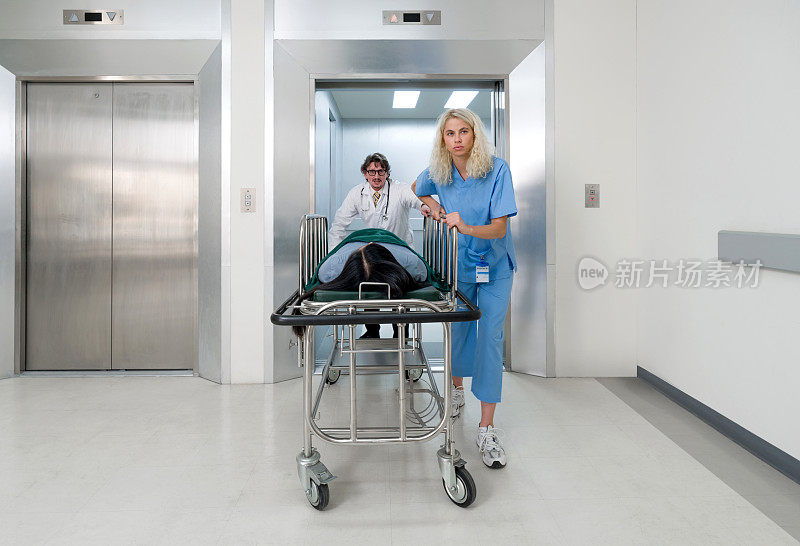 一名护士和一名医生推着一辆轮式担架，把病人从电梯里抬到医院的急诊室。