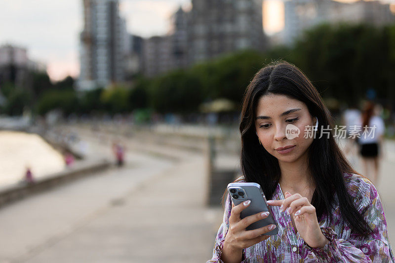 衣着讲究的年轻女子正在用便携式设备查看邮件。