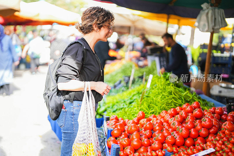 一名妇女在农贸市场拿着网购买水果和蔬菜