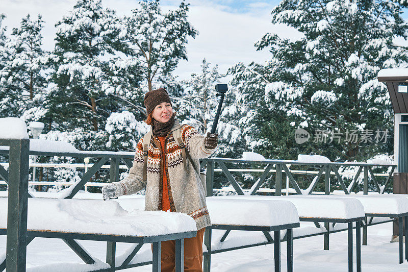 下雪后，一位女游客正试图清除咖啡桌上的雪