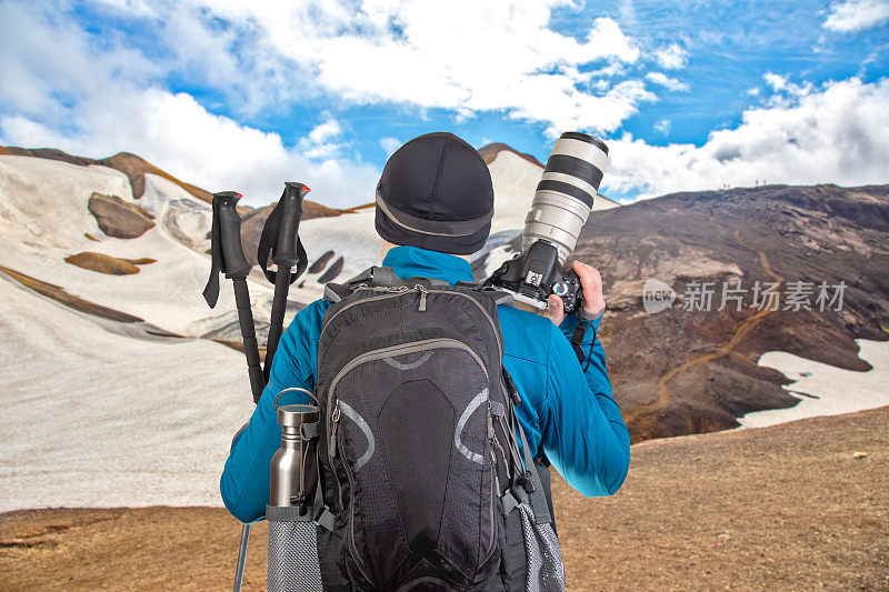男旅游摄影师背着背包，在群山中欣赏大自然之美。大自然在山间漫步