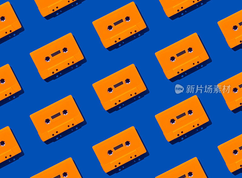 图案与蓝色背景上的复古橙色音频磁带。复古科技的创意理念。80的审美。老式音频盒式磁带模式的想法。复古的怀旧。平的。