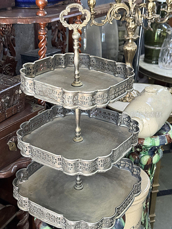古董店银饼架的特写图像，橱柜，桌子，玻璃器皿，石器床暖，重点在前景
