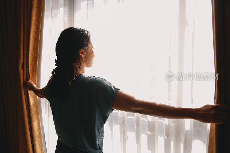 亚洲女人打开卧室的窗帘