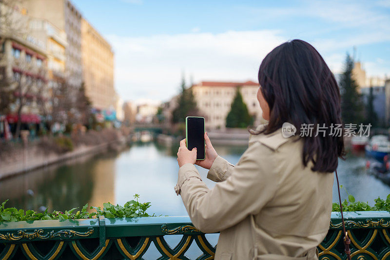 亚洲女人用手机拍照，在城里旅行。