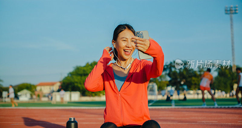 年轻的亚洲女运动员跑步者在锻炼后与健身教练进行在线视频通话，一边喝水一边挥舞着智能手机。健康的锻炼。