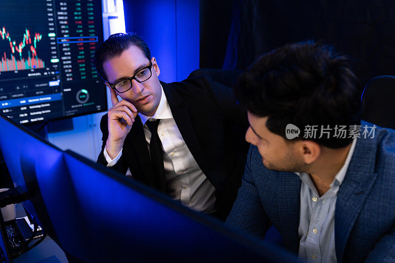 两个证券交易所的交易员在数据监视器上讨论市场。适于销售的。