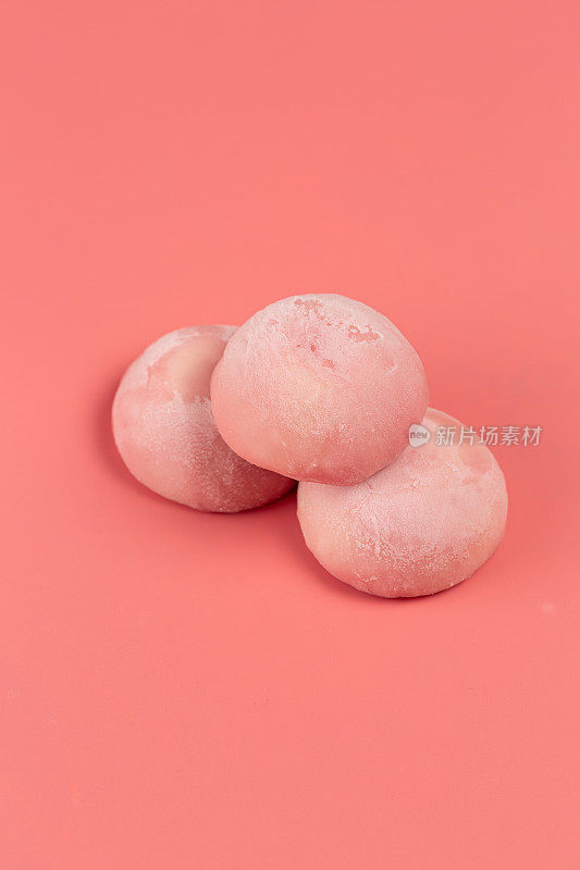 传统的日本甜点，糯米饼在粉红色的背景上用粉红色的米团做成，空间开阔