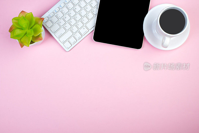 粉红色的办公桌子上有电脑，钢笔和一杯咖啡，很多东西。带复制空间的俯视图。