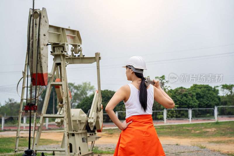 工程师在明亮的蓝天下使用手动工具检查泵千斤顶和钻井平台。在工作区域穿着防护服工作的工程师