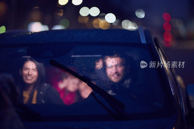 在夜晚，一个幸福的家庭在车里一起享受夜晚的公路旅行，在车灯的照耀下，充满了笑声和欢乐