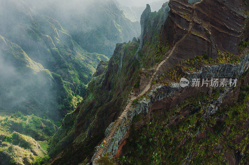 鸟瞰女人和男人在楼梯上徒步旅行在戏剧性的极端山区地形马德拉岛