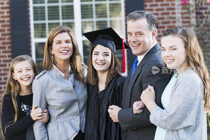 家庭与女儿在毕业帽和长袍