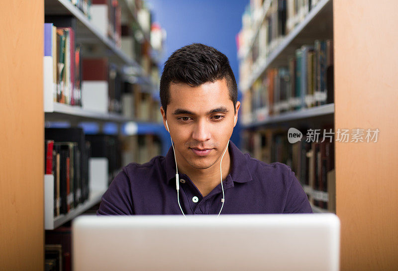 一个年轻的大学生在图书馆用笔记本电脑