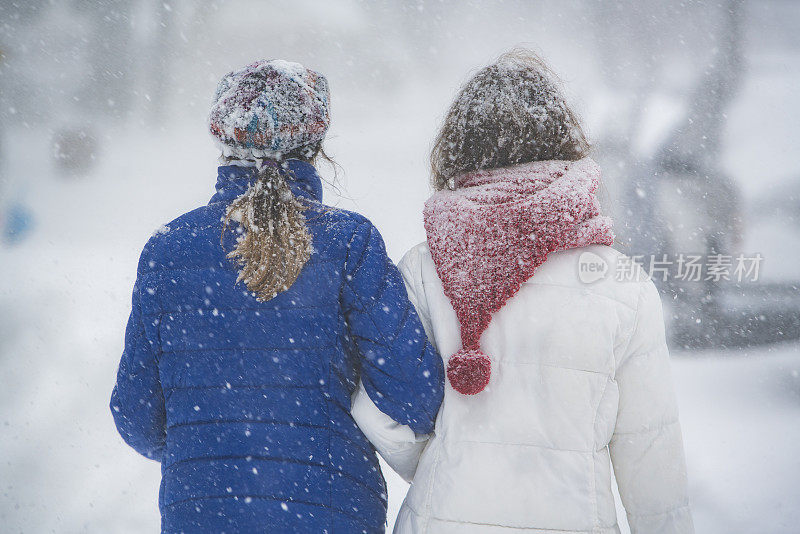 两个十几岁的女孩在下雪的街道上