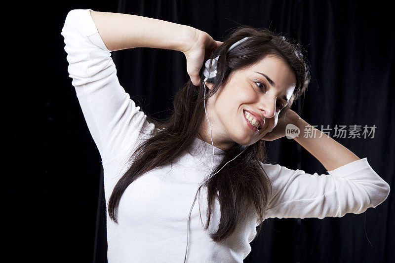 微笑的女人戴着耳机听音乐